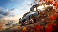 a car driving down a road surrounded by fall leaves in the background is a truck