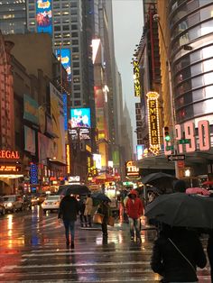 people are walking in the rain with umbrellas on a city street at night time