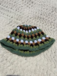 two crocheted hats sitting on top of a white carpet next to each other