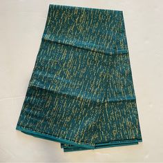 two pieces of cloth folded on top of each other with gold and green writing all over them