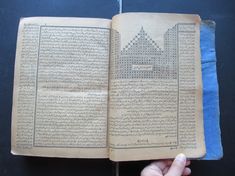 an open book with arabic writing on the pages and in human hands, against a black background