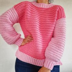 a woman is wearing a pink sweater and blue jeans with her hands on her hips