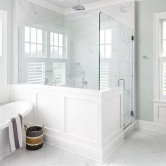 a white bathroom with marble tile flooring and walls, along with a claw - foot tub