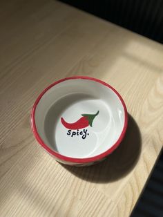 a red and white bowl sitting on top of a wooden table