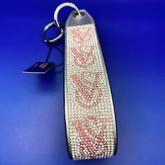 a pink and white beaded key chain on a blue surface with a tag attached to it