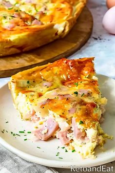 a slice of ham and cheese quiche on a plate with an egg in the background