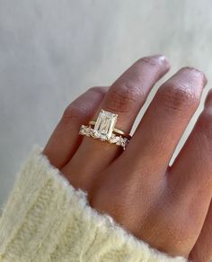 a woman's hand with a ring on it and an engagement band in the middle