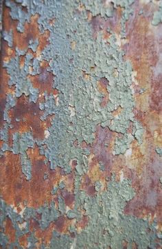 an old rusted metal surface with green and brown paint on it's sides