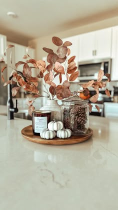 a white counter top topped with jars filled with plants and spices next to a wooden tray