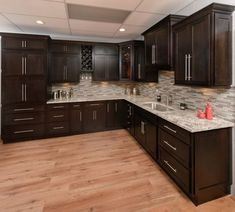 a large kitchen with dark wood cabinets and marble counter tops, along with hardwood flooring