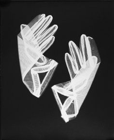 two white gloves sitting next to each other on top of a black surface with one glove in the middle