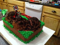 a cake shaped like a dirt bike on top of green grass in the shape of a heart