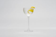 a glass filled with white liquid and lemon wedges on the rim, sitting on a plain surface