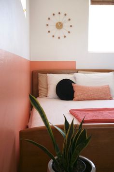 a bedroom with a bed, plant and clock on the wall