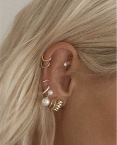 a woman with blonde hair wearing three different ear piercings and two pearled earrings