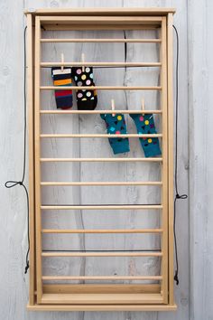 a wooden frame with clothes pegs hanging from it's sides on a white wall