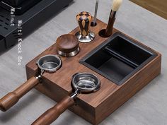 a wooden case with metal cups and spoons in it on a table next to a speaker