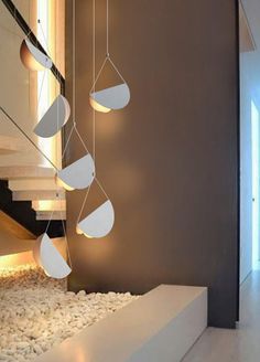 some lights hanging from the ceiling in front of a stair case with white pebbles on it