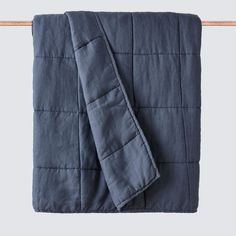 a blue quilted blanket hanging on a clothes line with an orange wooden hanger