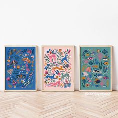 three framed art prints featuring tropical animals and plants on a chevron wood floor in front of a white wall