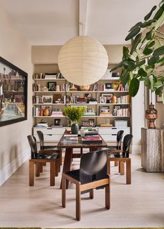 a dining room table surrounded by chairs and bookshelves