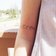 a woman's arm with a small mountain tattoo on the left side of her arm