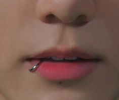 a woman's lips are shown with piercings on her nose and lip ring