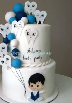 a white cake with blue and white balloons on it's side, featuring a boy holding onto the top tier