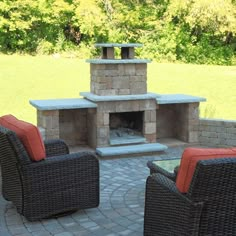 two wicker chairs sitting in front of an outdoor fireplace