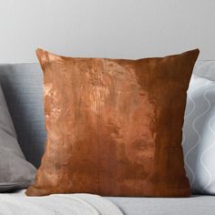 a brown leather pillow sitting on top of a couch next to a white throw pillow