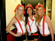 three young women dressed in costumes posing for the camera with one woman wearing a fireman's hat