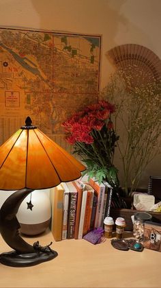 a lamp sitting on top of a desk next to a book case and vase with flowers