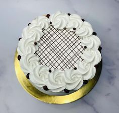 a cake with white frosting and chocolate sprinkles on a gold plate