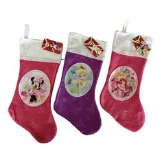 three christmas stockings with disney characters hanging from the top one is pink, purple and white