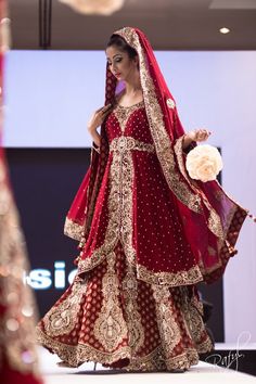 a woman in a red and gold bridal gown walks down the runway at a fashion show