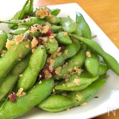 a white plate topped with green beans covered in seasoning next to a wooden table