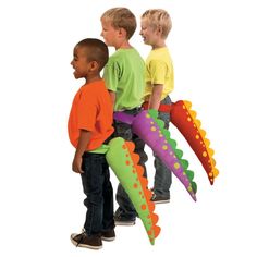 three children are standing in front of an assortment of toy dinosaurs that look like alligators