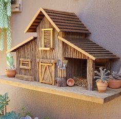 a small wooden house on a shelf with succulents and cacti