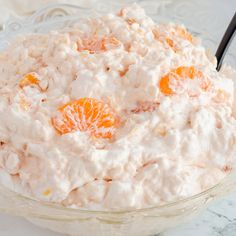 a bowl filled with oranges and cream on top of a marble countertop next to a black spoon