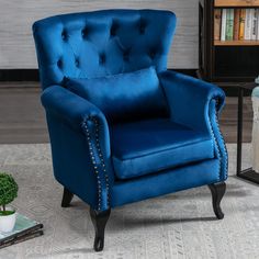 a blue chair sitting on top of a rug next to a book shelf and potted plant