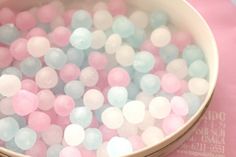 a bowl filled with lots of pink and blue confetti on top of a table