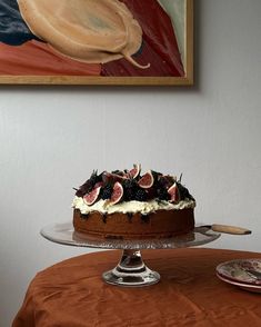 a cake sitting on top of a glass platter next to a plate with fruit