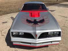 a silver and red car parked on top of a dirt field