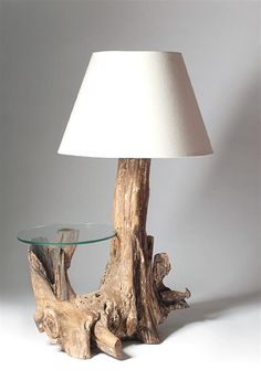 a table with a lamp on top of it next to a tree stump and a white shade