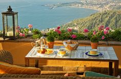 the table is set with breakfast on the terrace overlooking the ocean