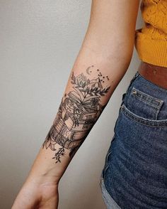 a woman's arm with a tattoo on it that has books and flowers on it