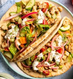 two pita breads filled with vegetables and chicken on top of a blue plate