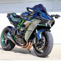 a blue and black motorcycle parked in front of a white garage door with its lights on