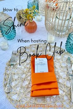 an orange napkin sitting on top of a table next to silverware and vases