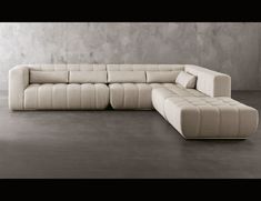 a large white couch sitting on top of a wooden floor next to a gray wall